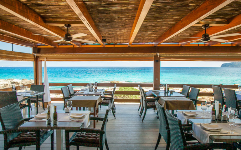 Restaurante con puesta de sol en Ibiza | Hostal boutique en San Antonio Ibiza Terraza de restaurante frente al mar para cenar al atardecer en Ibiza, recomendada por un hostal boutique en San Antonio Ibiza.