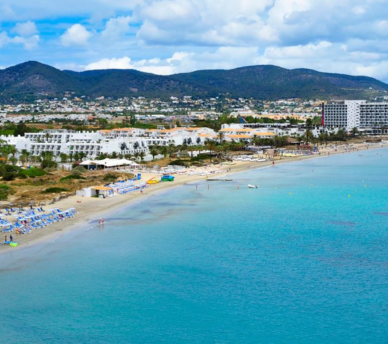 Playa urbana de Ibiza con arena clara, paseo marítimo y servicios, una opción fácil para visitar desde un hostal boutique en San Antonio Ibiza